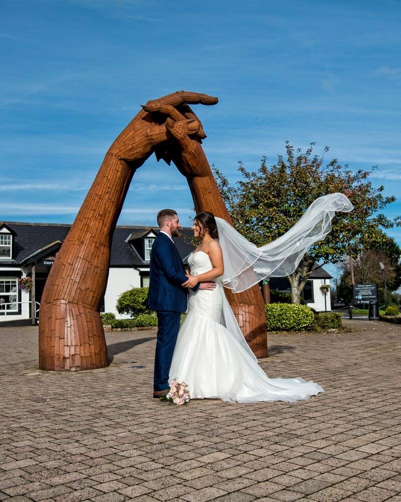 Wedding photo in front of the joined hands sculpture at the Famous Blacksmiths Shop in Gretna Green