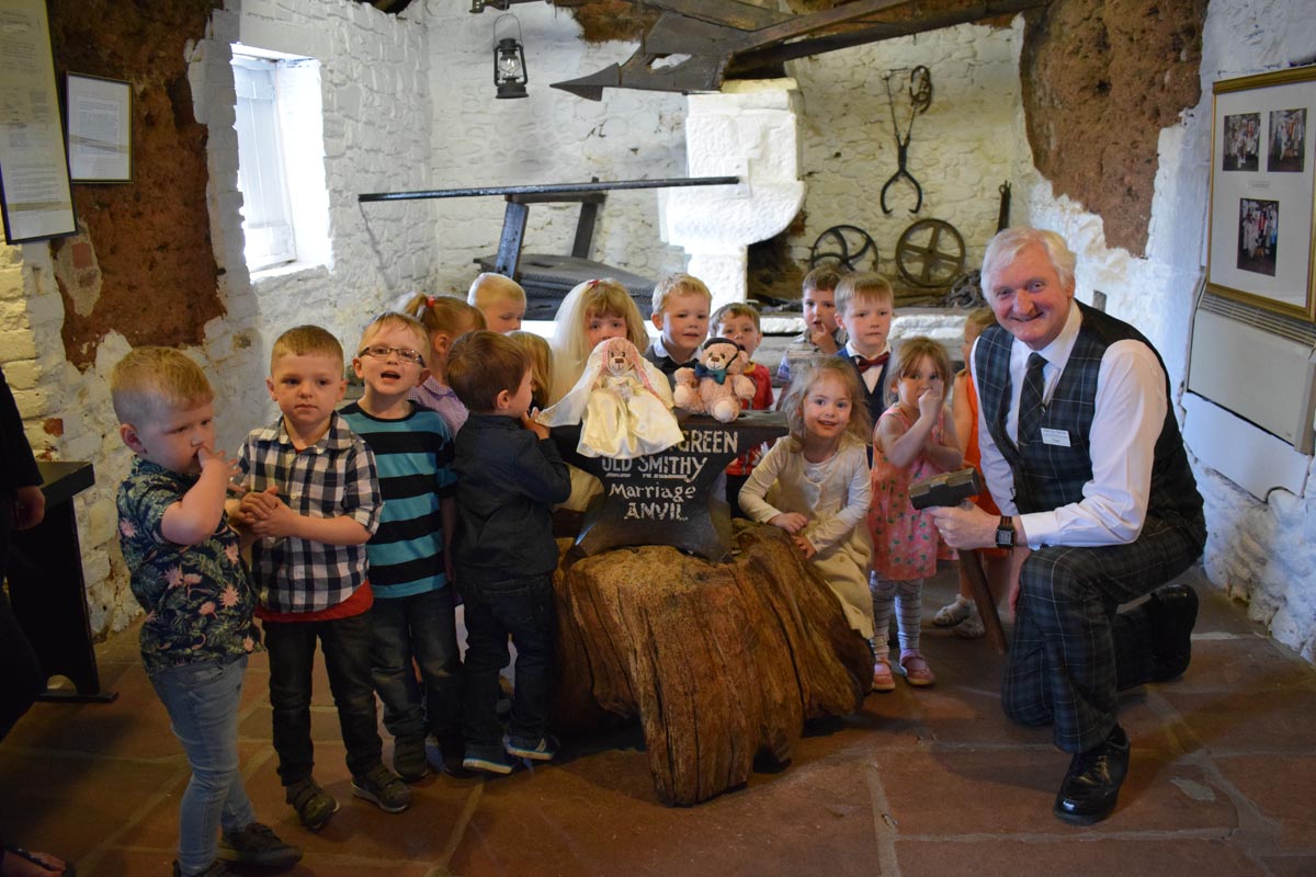 Frank Clarkson welcomes a group of nursery children to the Famous Blacksmiths Shop