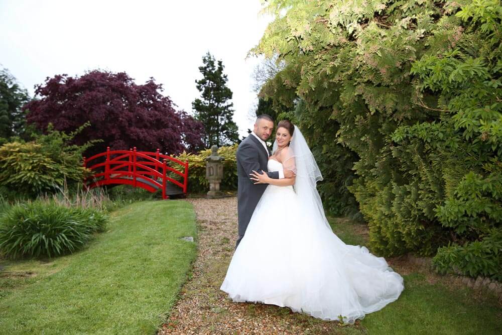 Wedding photo on the red bridge at Greens Hotel Water Gardens, Gretna